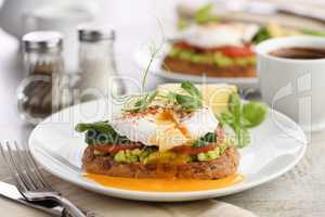 Eggs Benedict with guacamole on cereal bread