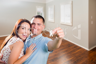 Young Military Couple Showing Off House Keys in Empty Room of Ne