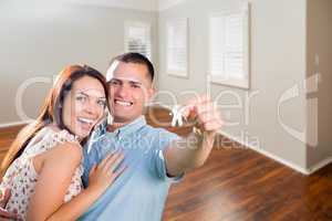 Young Military Couple Showing Off House Keys in Empty Room of Ne