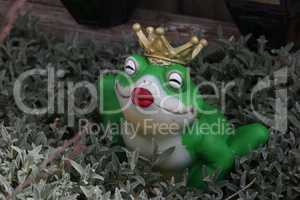 Decorative frog princess among plants in the garden