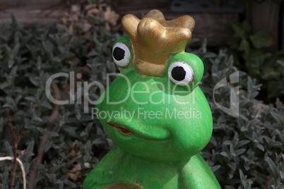 Decorative frog princess among plants in the garden