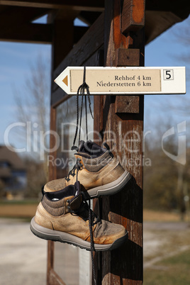 Hiking shoes hang on a post with the directional signs