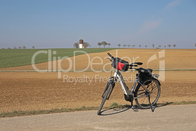 The e-bike stands near a plowed field