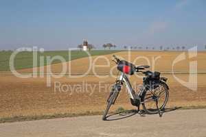 The e-bike stands near a plowed field