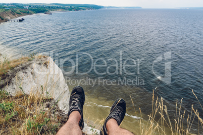 point of view of man sitting on the edge of cliff