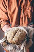 Man holds a freshly baked rye bread