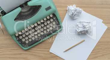 A vintage typewriter with paper sheets, stencil and paper balls.