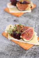 Cracker with a slice of camembert with confiture and figs