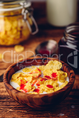 Breakfast with corn flakes, milk and berry syrup
