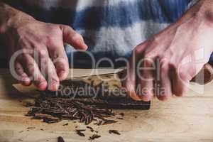 Chopping dark chocolate bar with knife