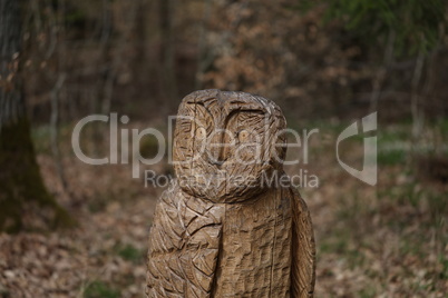 An owl cut from a tree stands in the forest