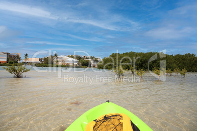 Sun shines through the clouds over a Green Kayak in the water of