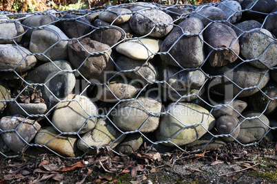 A wall of round stones held by metal mesh