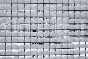 Fencing mesh with leftover white snow in winter