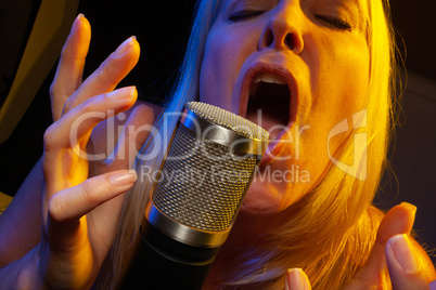 Female vocalist under gelled lighting sings with passion into co
