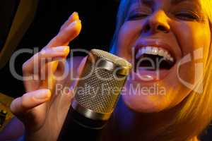 Female vocalist under gelled lighting sings with passion into co