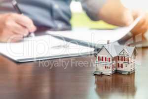 Man signing real estate contract papers with small model home in