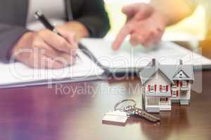 Real estate agent and customer sign contract papers with house k