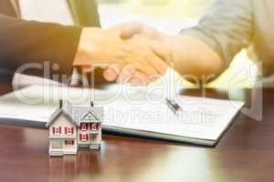 Real estate agent and customer sign contract papers and shake ha