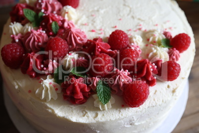Birthday cake with cream and fresh raspberries