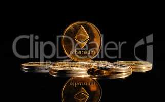 Closeup golden coin with Ether logo. New cryptocurrency Ethereum ETH 2.0 on a top of bitcoin coins against black background. A heap of decentralized digital currency. Crypto payment. Electronic money