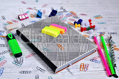 Notepad, paperclips, buttons, pencils, marker on a light backgro