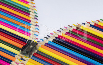Background photo of colored pencils and a sharpener forming an i