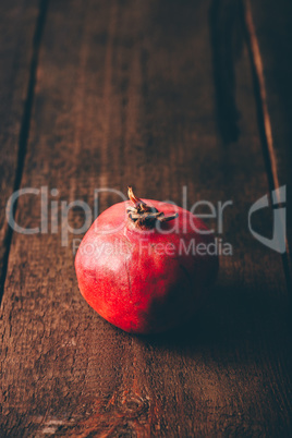 One red pomegranate on wooden surface