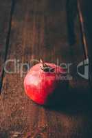 One red pomegranate on wooden surface