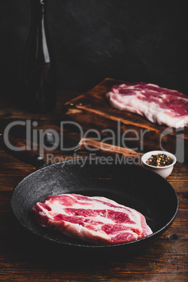 Raw pork neck steak in skillet
