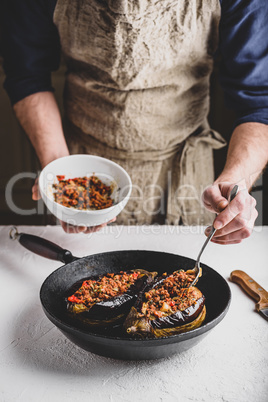 Preparing eggplants stuffed with ground beef, tomatoes and spices