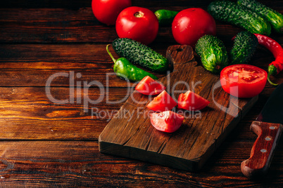 Sliced tomatoes on cutting board and cucumbers with chili pepper