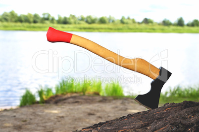 a beautiful-shaped ax sticks out in a tree, with a yellow handle