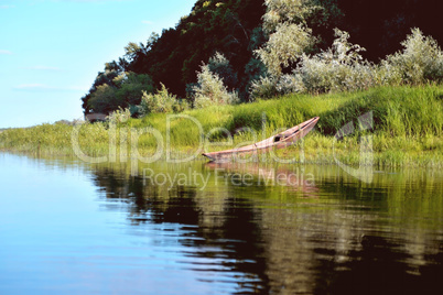 old wooden boat on the river bank close up against the backgroun