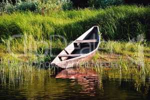old wooden boat on the river bank close up against the backgroun