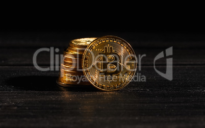 Closeup golden coin with bitcoin logo. Leader in cryptocurrency Bitcoin BTC on a top of coins against black wooden surface. Pile of decentralized digital currency. Crypto payment. Electronic money.