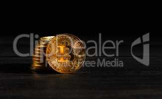 Closeup golden coin with bitcoin logo. Leader in cryptocurrency Bitcoin BTC on a top of coins against black wooden surface. Pile of decentralized digital currency. Crypto payment. Electronic money.