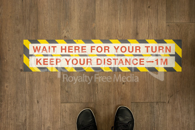 Wait your turn, keep your distance sign on a store floor.