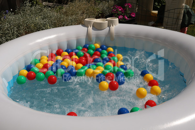 Multicolored balls float in the bubbling water of an inflatable pool