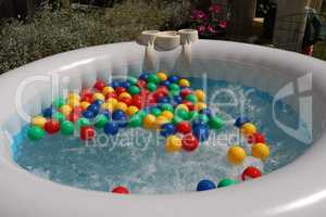 Multicolored balls float in the bubbling water of an inflatable pool