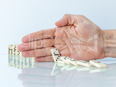 Hand stopping domino effect on white background.