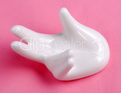 Ceramic stand with hand shape on pink background