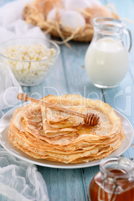 A stack of thin pancakes with honey