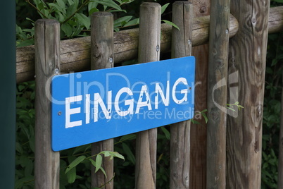 Sign on a wooden fence in German - Entrance
