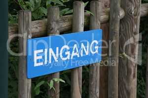 Sign on a wooden fence in German - Entrance