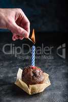 Hand lighting candle on birthday muffin