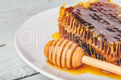 Honeycomb on plate with honey dipper