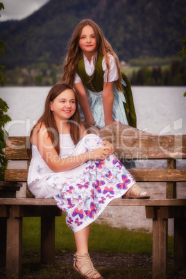 Zwei langhaarige junge Mädchen auf einer Bank