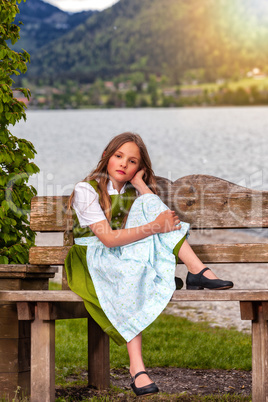 Porträt eines  Mädchens sitzend im Dirndl auf einer Bank