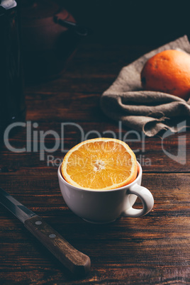 Half of orange in a white cup